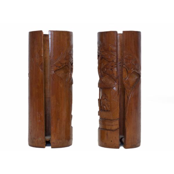 L’arrière des deux vases en bois. Une section est découpée au centre de chaque vase. Une partie d’une image sculptée d’une structure couverte est visible. 