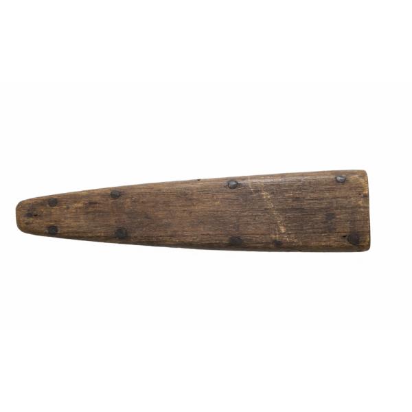 Un fourreau en bois brun, pointant vers la gauche. Il y a une rangée de quatre clous métalliques le long des bords supérieur et inférieur.