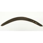 A brown, wooden boomerang. It is curved and there are three holes in one end that are stuffed with paper.  