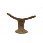 A straight-on view of a wooden head rest. A curved piece sits on top of a base that widens at the bottom and has a series of ridges around it.