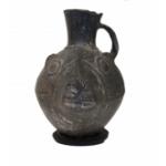 Front view of black stirrup-handle jug, shaped like a llama's head. 