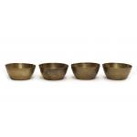 Front view of four brass finger bowls with flared sides and flat bottoms.  