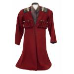 Front of a Cossack uniform made for a child. It is red in colour and has a v-neck. There are pockets for bullets on the breast and there are blue and gold patches on the shoulders.