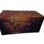 The front of a carved cedar chest. There are scenes carved into the lid and side showing people, trees, and buildings. There are golden corners and openers on the box. 
