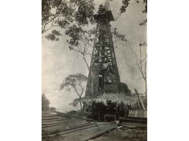 Thatched derrick with casing laying on the ground. 