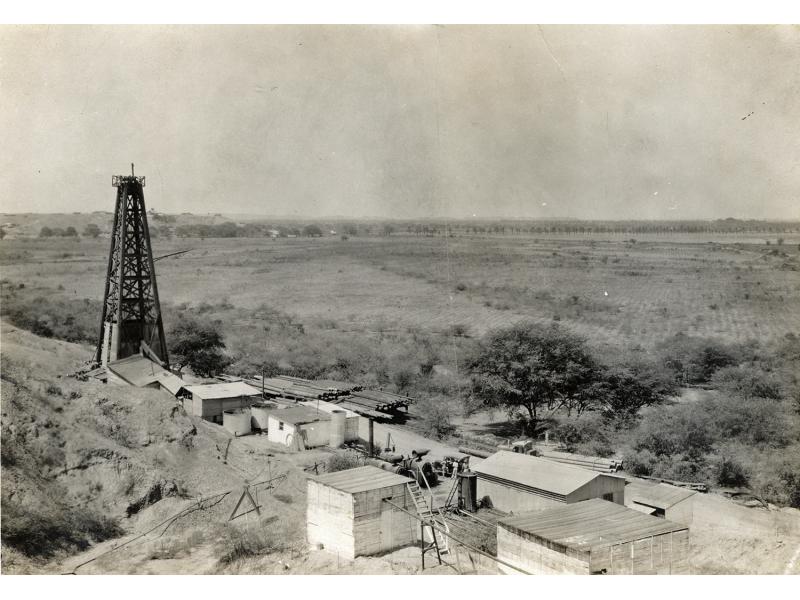Installation de forage pétrolier avec des piles de rondins et de tubage, au milieu d’une plaine. 