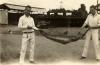 Irwin et Lovelady Holding tenant un boa constrictor entre eux. Ils sont sur une route de terre et il y a des bâtiments derrière eux. Ils portent une chemise et des pantalons blancs. 