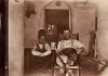 Une photo de Humphrey Tracy étendu sur une chaise, un verre à la main. Un garçon est accroupi à côté de lui. 